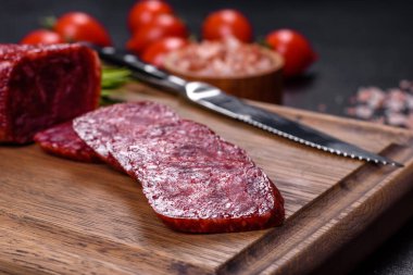 Taze biberiye ve baharatlı salam. Siyah taştan bir arka planda