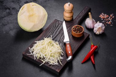 Bir parça lahana kafası ve kesilmiş lahana salatası. Koyu beton arka planda ahşap kesim tahtası.