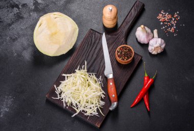 Bir parça lahana kafası ve kesilmiş lahana salatası. Koyu beton arka planda ahşap kesim tahtası.