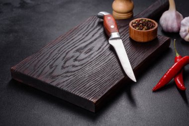 İçinde bıçak, çatal ya da kaşık olan boş bir tabak. Koyu beton arka planda tahta kesim tahtası var. Ev aletleri ve ev yemeği malzemelerinin hazırlanması