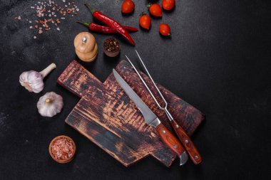 İçinde bıçak, çatal ya da kaşık olan boş bir tabak. Koyu beton arka planda tahta kesim tahtası var. Ev aletleri ve ev yemeği malzemelerinin hazırlanması