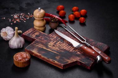 İçinde bıçak, çatal ya da kaşık olan boş bir tabak. Koyu beton arka planda tahta kesim tahtası var. Ev aletleri ve ev yemeği malzemelerinin hazırlanması