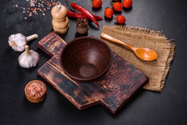 İçinde bıçak, çatal ya da kaşık olan boş bir tabak. Koyu beton arka planda tahta kesim tahtası var. Ev aletleri ve ev yemeği malzemelerinin hazırlanması