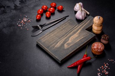 İçinde bıçak, çatal ya da kaşık olan boş bir tabak. Koyu beton arka planda tahta kesim tahtası var. Ev aletleri ve ev yemeği malzemelerinin hazırlanması