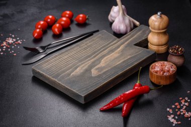 İçinde bıçak, çatal ya da kaşık olan boş bir tabak. Koyu beton arka planda tahta kesim tahtası var. Ev aletleri ve ev yemeği malzemelerinin hazırlanması