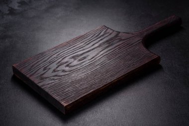 İçinde bıçak, çatal ya da kaşık olan boş bir tabak. Koyu beton arka planda tahta kesim tahtası var. Ev aletleri ve ev yemeği malzemelerinin hazırlanması