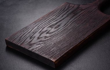 İçinde bıçak, çatal ya da kaşık olan boş bir tabak. Koyu beton arka planda tahta kesim tahtası var. Ev aletleri ve ev yemeği malzemelerinin hazırlanması