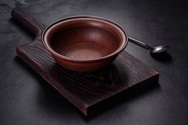 İçinde bıçak, çatal ya da kaşık olan boş bir tabak. Koyu beton arka planda tahta kesim tahtası var. Ev aletleri ve ev yemeği malzemelerinin hazırlanması