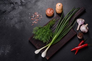 Taze soğan, dereotu, sarımsak ve acı biberin yanı sıra baharatlar ve baharatlar, geleneksel Ukrayna borsasının hazırlanmasında kullanılacak malzemeler olarak ahşap bir kesme tahtasının üzerinde.