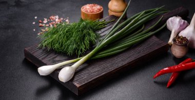 Taze soğan, dereotu, sarımsak ve acı biberin yanı sıra baharatlar ve baharatlar, geleneksel Ukrayna borsasının hazırlanmasında kullanılacak malzemeler olarak ahşap bir kesme tahtasının üzerinde.