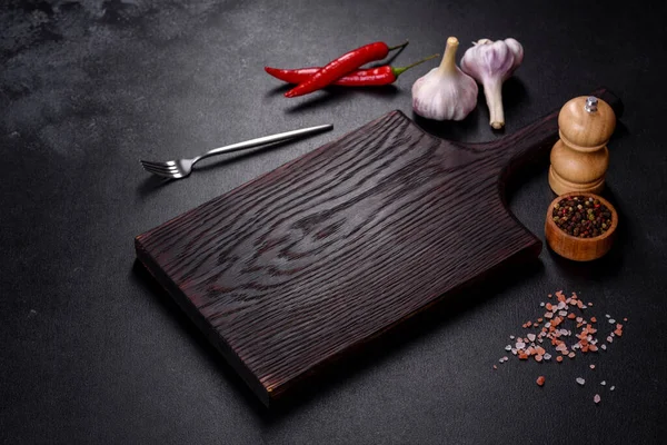叉子或勺子在黑暗的混凝土背景上用木板切割板的空盘子 家庭烹调用具和配料的制备 — 图库照片