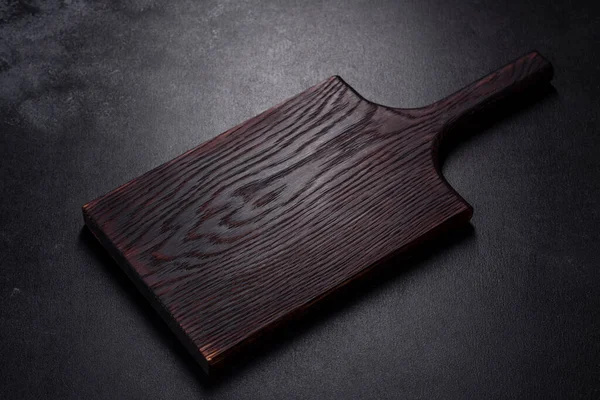 İçinde bıçak, çatal ya da kaşık olan boş bir tabak. Koyu beton arka planda tahta kesim tahtası var. Ev aletleri ve ev yemeği malzemelerinin hazırlanması