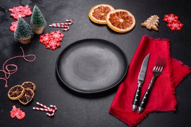 Boş siyah seramik tabağı, köknar ağacı dalı ve siyah aksesuarlı siyah taş zemin