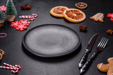 Boş siyah seramik tabağı, köknar ağacı dalı ve siyah aksesuarlı siyah taş zemin