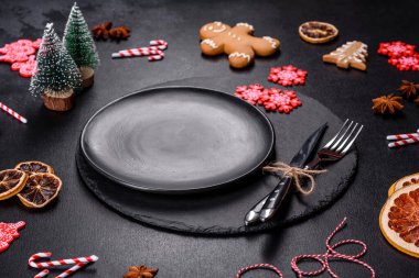 Boş siyah seramik tabağı, köknar ağacı dalı ve siyah aksesuarlı siyah taş zemin