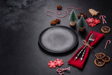 Boş siyah seramik tabağı, köknar ağacı dalı ve siyah aksesuarlı siyah taş zemin