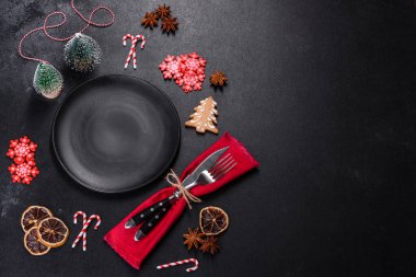 Boş siyah seramik tabağı, köknar ağacı dalı ve siyah aksesuarlı siyah taş zemin