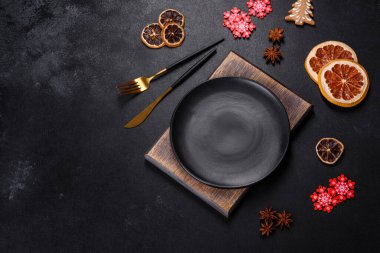 Boş siyah seramik tabağı, köknar ağacı dalı ve siyah aksesuarlı siyah taş zemin