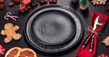 Boş siyah seramik tabağı, köknar ağacı dalı ve siyah aksesuarlı siyah taş zemin