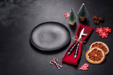 Boş siyah seramik tabağı, köknar ağacı dalı ve siyah aksesuarlı siyah taş zemin