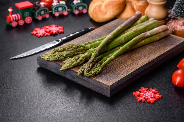 喜庆的圣诞桌上 美味的新鲜绿色芦笋梗在木制切菜板上 — 图库照片