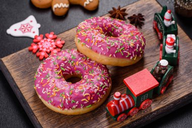 Pembe jöleli ve koyu beton arka planda renkli serpiştirilmiş güzel bir donut. Noel masasına şeker.
