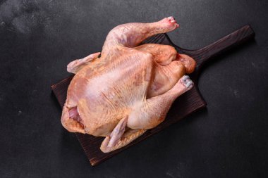 Çiğ hindi ya da tuz, baharat ve otlu tavuk. Ahşap bir kesme tahtasının üzerinde, koyu beton bir arka planda. Festival masası hazırlıyorum.