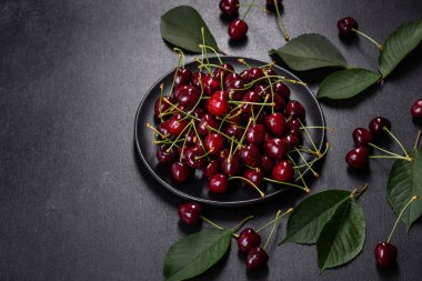Koyu beton bir zeminde taze kırmızı kiraz meyvesi. Kapat.