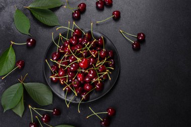 Koyu beton bir zeminde taze kırmızı kiraz meyvesi. Kapat.