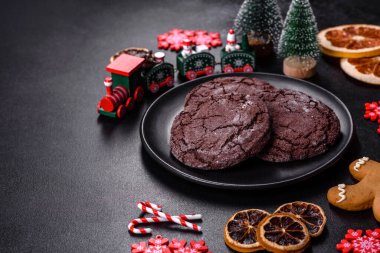 İçinde Noel oyuncakları, kurutulmuş turunçgiller ve oyuncak Noel ağaçları olan koyu betondan yapılmış lezzetli çikolatalı bisküviler. Festival masası hazırlıyorum.