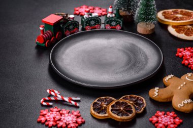 İçinde Noel oyuncakları, kurutulmuş turunçgiller ve oyuncak Noel ağaçları olan koyu betondan yapılmış lezzetli çikolatalı bisküviler. Festival masası hazırlıyorum.