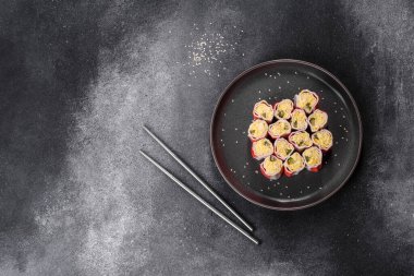 Koyu gri arka planda pirinç, yumurta ve yeşil soğanla doldurulmuş yengeç çubukları.