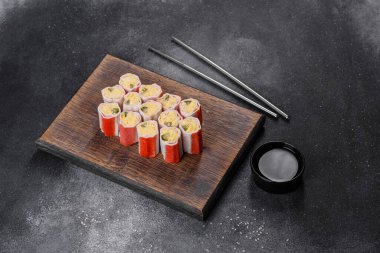 Koyu gri arka planda pirinç, yumurta ve yeşil soğanla doldurulmuş yengeç çubukları.