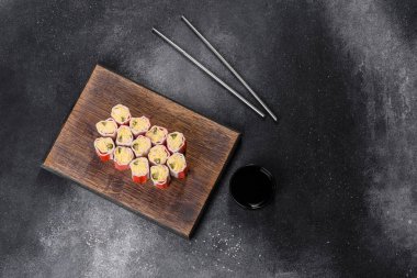 Koyu gri arka planda pirinç, yumurta ve yeşil soğanla doldurulmuş yengeç çubukları.