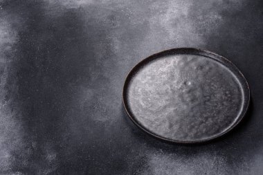 Empty black plates, fork and knife on a gray background. Top view, copy space