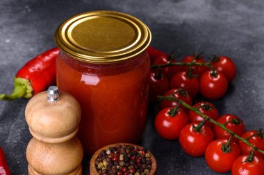 Spicy sweet tomato sauce with garlic, pepper and herbs in a glass jars. Canned tomatoes in tomato juice