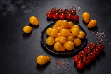 Pear-shaped small yellow tomatoes in a ceramic plate on a dark concrete table. Salad ingredients