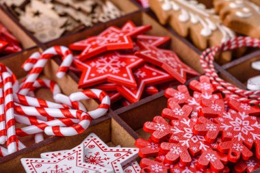 Christmas toys in white and red in a wooden sectional box against a dark concrete background. Home decorations for Christmas holiday