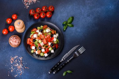 Domates, salatalık, bel biberi, zeytin ve siyah tabakta beyaz peynir ile taze Yunan salatası.