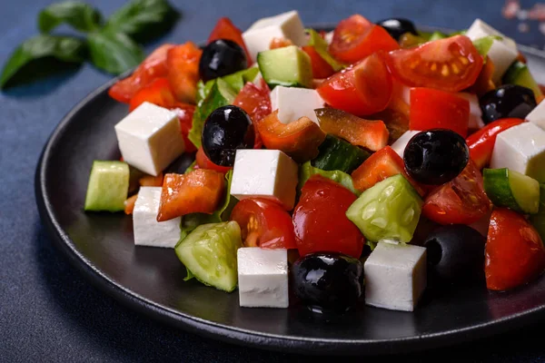 Fresh greek salad with tomato, cucumber, bel pepper , olives and feta cheese on black plate