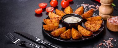 Baked potato wedges with cheese and herbs and tomato sauce on a dark background - homemade organic vegetable vegan vegetarian potato wedges snack food