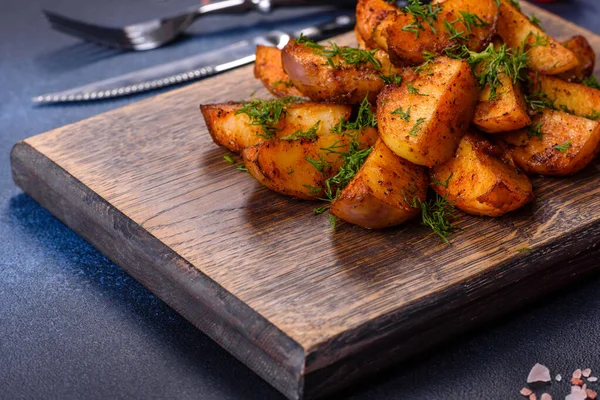 Baked potato wedges with cheese and herbs and tomato sauce on a dark background - homemade organic vegetable vegan vegetarian potato wedges snack food