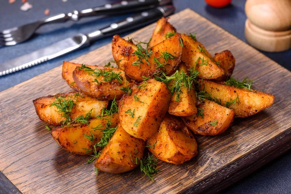 Baked potato wedges with cheese and herbs and tomato sauce on a dark background - homemade organic vegetable vegan vegetarian potato wedges snack food