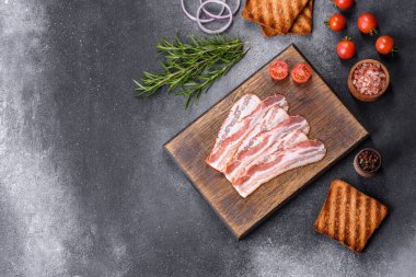Raw smoked bacon on a wooden board with several cut pieces