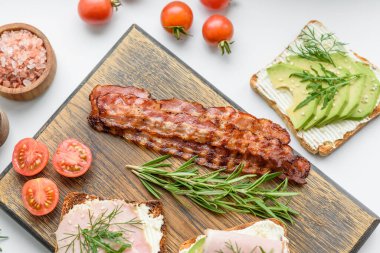 Fresh, delicious ham, butter, avocado and sesame seeds sandwiches on a wooden cutting board. Delicious healthy food