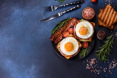 Fresh, delicious sandwiches with fried egg, ham, butter, avocado and sesame seeds on a wooden cutting board. Delicious healthy food