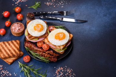 Fresh, delicious sandwiches with fried egg, ham, butter, avocado and sesame seeds on a wooden cutting board. Delicious healthy food