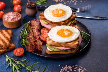 Fresh, delicious sandwiches with fried egg, ham, butter, avocado and sesame seeds on a wooden cutting board. Delicious healthy food