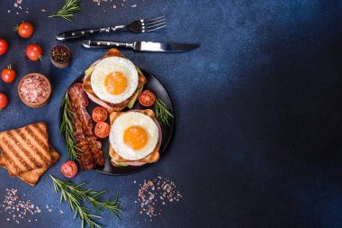Fresh, delicious sandwiches with fried egg, ham, butter, avocado and sesame seeds on a wooden cutting board. Delicious healthy food