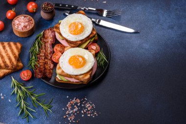Fresh, delicious sandwiches with fried egg, ham, butter, avocado and sesame seeds on a wooden cutting board. Delicious healthy food